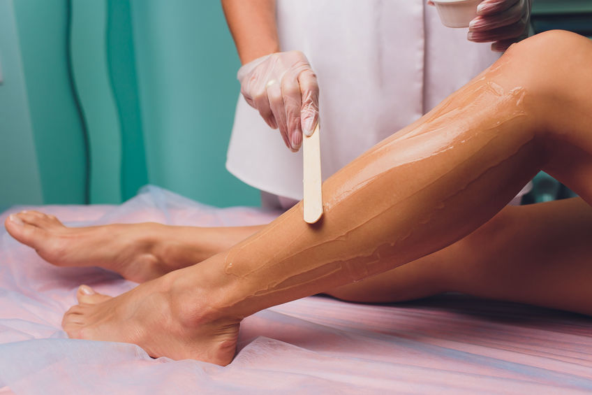 applying the cream with wax stick on legs